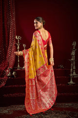 Woman in a red and yellow saree standing against a red background