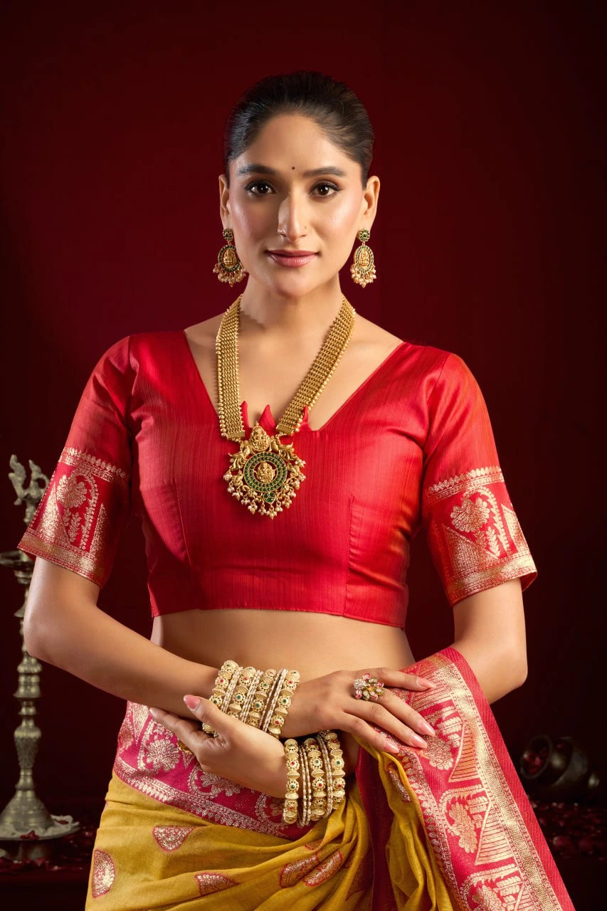Woman in traditional red and yellow saree with jewelry against a dark background
