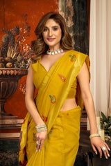 Woman in a yellow saree with floral patterns in an indoor setting