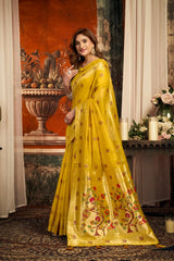 Woman in a yellow saree with floral patterns in an indoor setting.