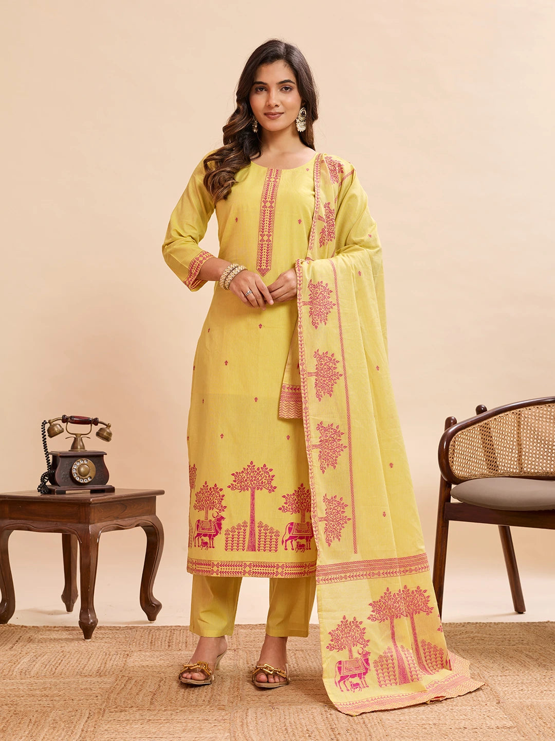 Woman wearing a yellow traditional outfit with pink patterns on a beige background