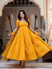 Woman in a yellow dress with white patterns standing in an ornate doorway.