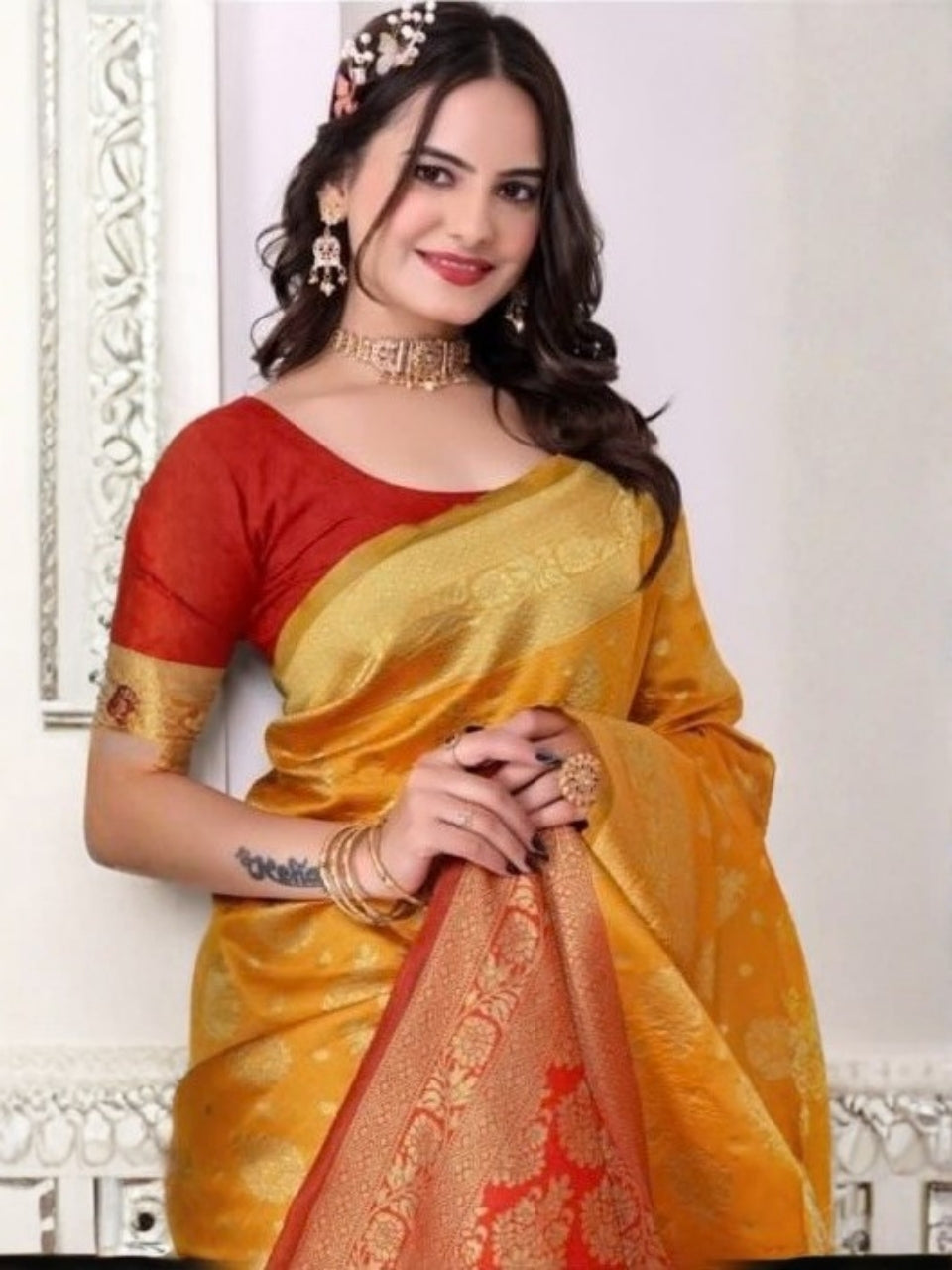 Woman wearing a yellow and red saree with jewelry against a white background