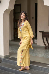 Woman in a yellow outfit with floral patterns standing on steps.