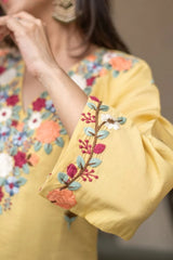 Yellow embroidered sleeve with floral patterns on a blurred background