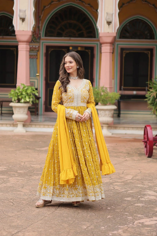 Woman in a yellow and white traditional outfit standing in front of an ornate building.