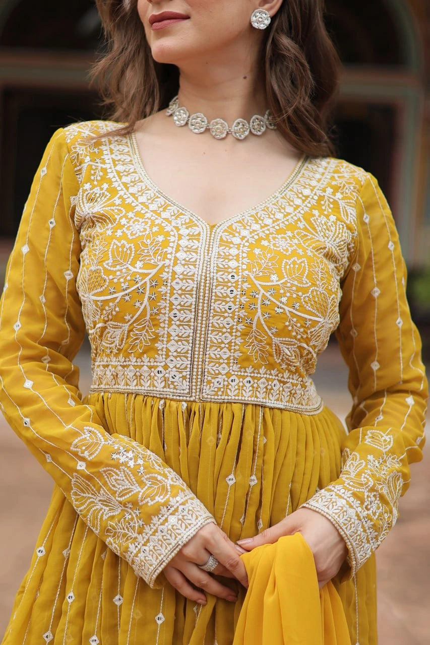 Woman wearing a yellow traditional outfit with intricate white embroidery.