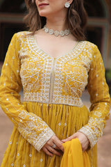 Woman wearing a yellow traditional outfit with intricate white embroidery.