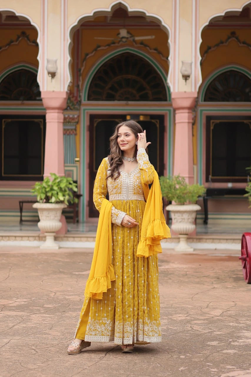 Woman in a yellow traditional outfit standing in front of a colorful architectural background