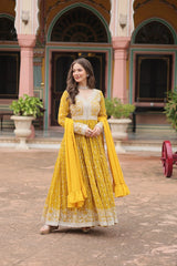 Woman in a yellow and white traditional outfit standing in front of an ornate building.