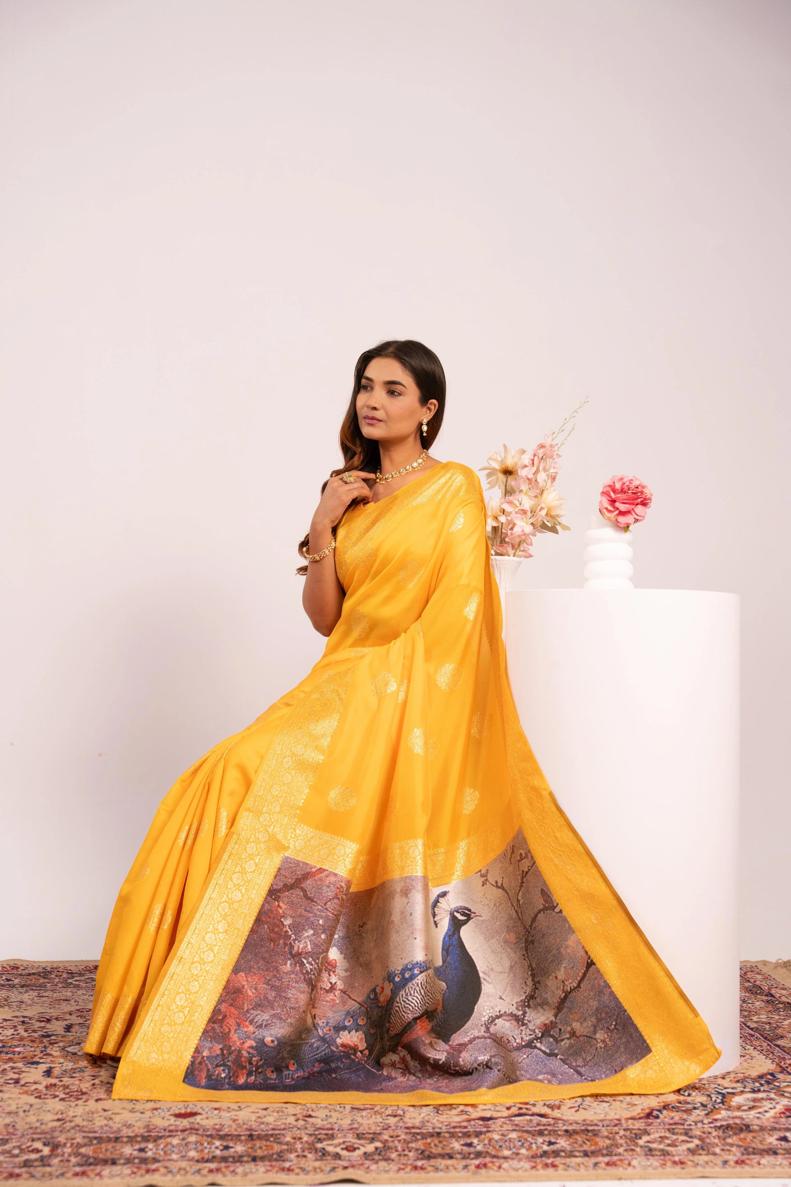 Woman in a yellow saree with peacock design on a white background