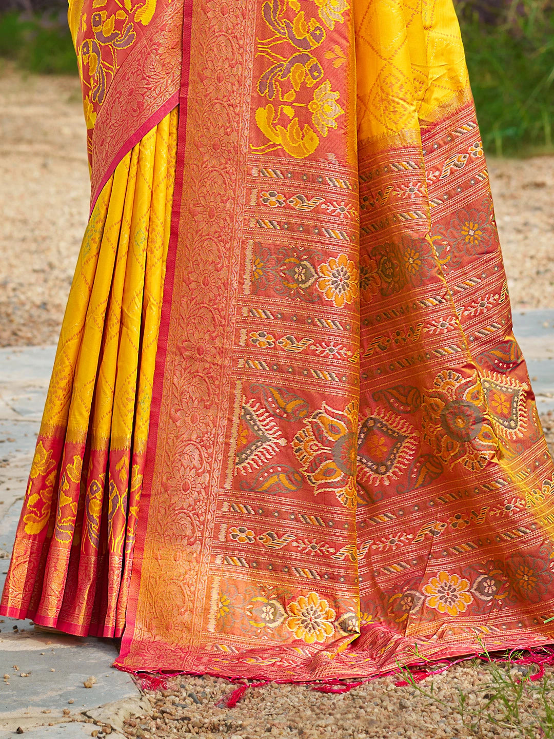 Traditional yellow and red saree with intricate patterns on a natural background