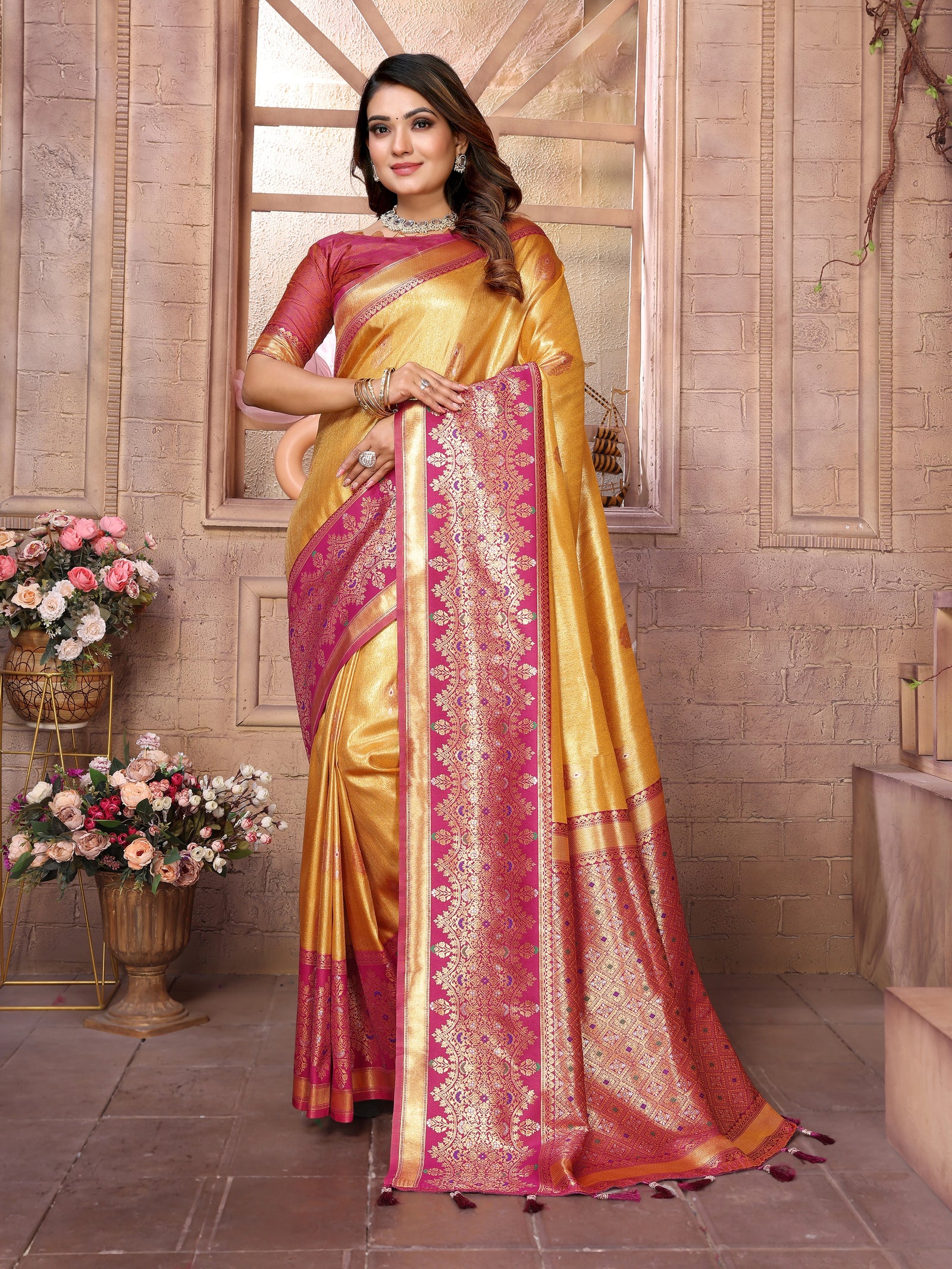 Woman wearing a yellow and pink saree with floral decorations in the background