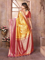 Woman wearing a yellow and red saree in an indoor setting with flowers and decor.