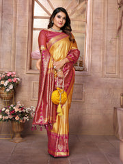 Woman in a yellow and pink saree holding a yellow bag in a decorated room.