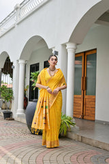 Woman in a yellow saree standing in front of a white building with columns.
