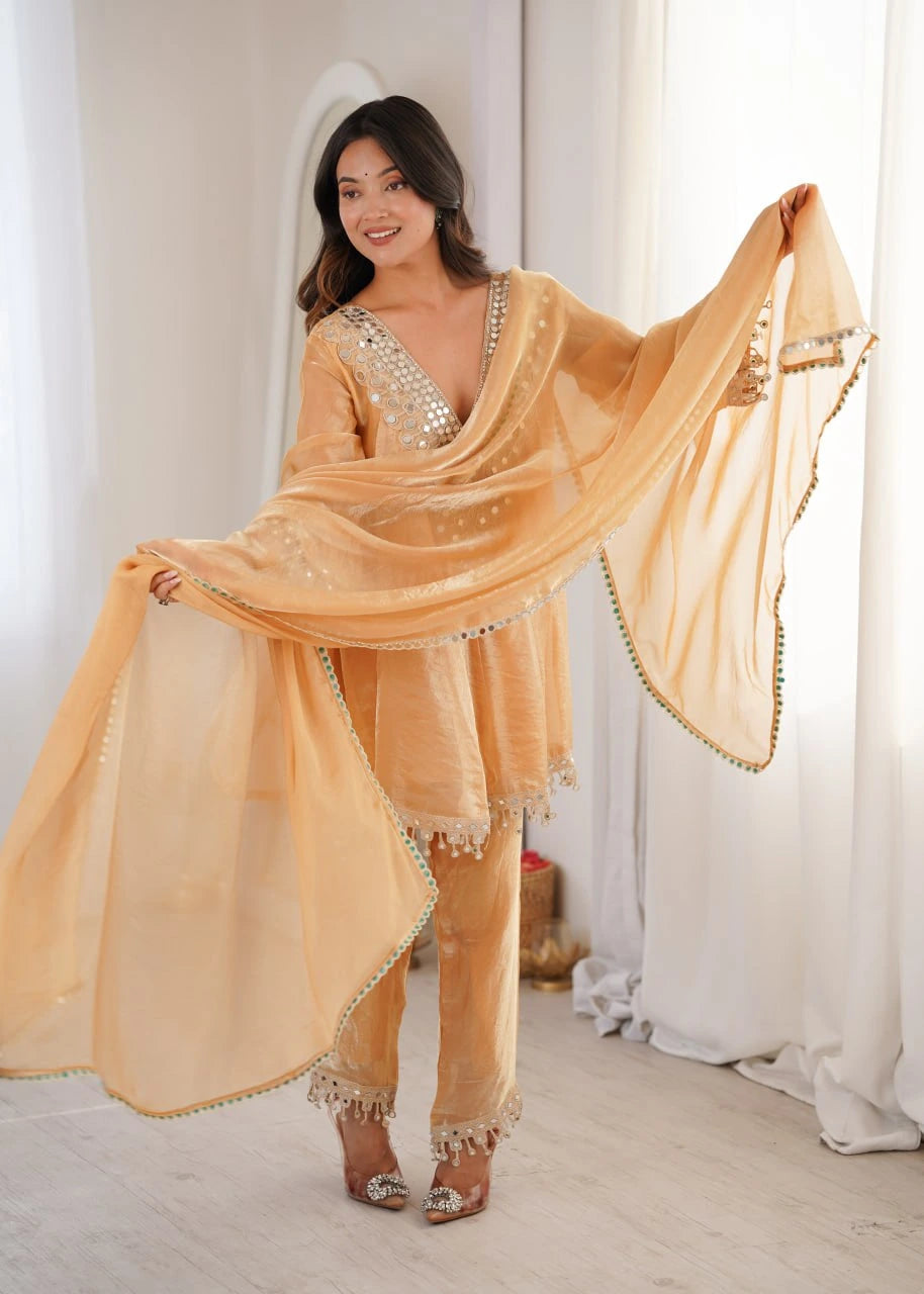 Woman wearing a peach-colored outfit with a matching shawl in a bright room.