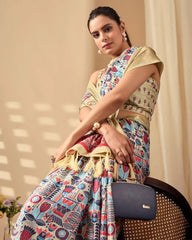 Woman draped in a cream saree featuring vibrant traditional prints, highlighted by an elegant gold zari border and pallu.