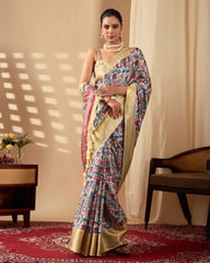 A woman wearing a cream saree with colorful folk-inspired prints and a rich golden woven border, paired with elegant pearl jewelry.