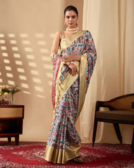 A woman wearing a cream saree with colorful folk-inspired prints and a rich golden woven border, paired with elegant pearl jewelry.