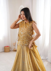 Woman wearing a mustard yellow traditional outfit with intricate designs indoors.