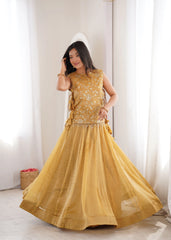 Woman wearing a mustard yellow traditional outfit with intricate patterns indoors.