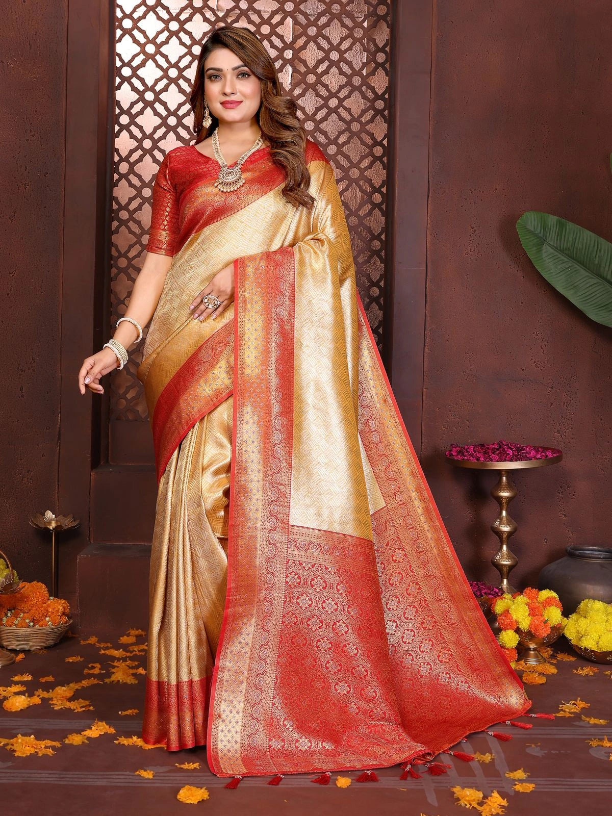 Woman wearing a red and beige saree with floral decorations on a brown background