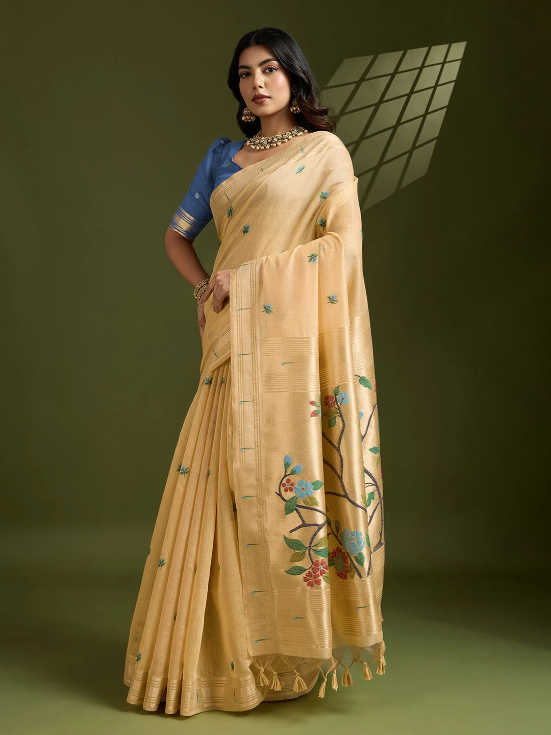Woman wearing a beige saree with floral patterns on a green background