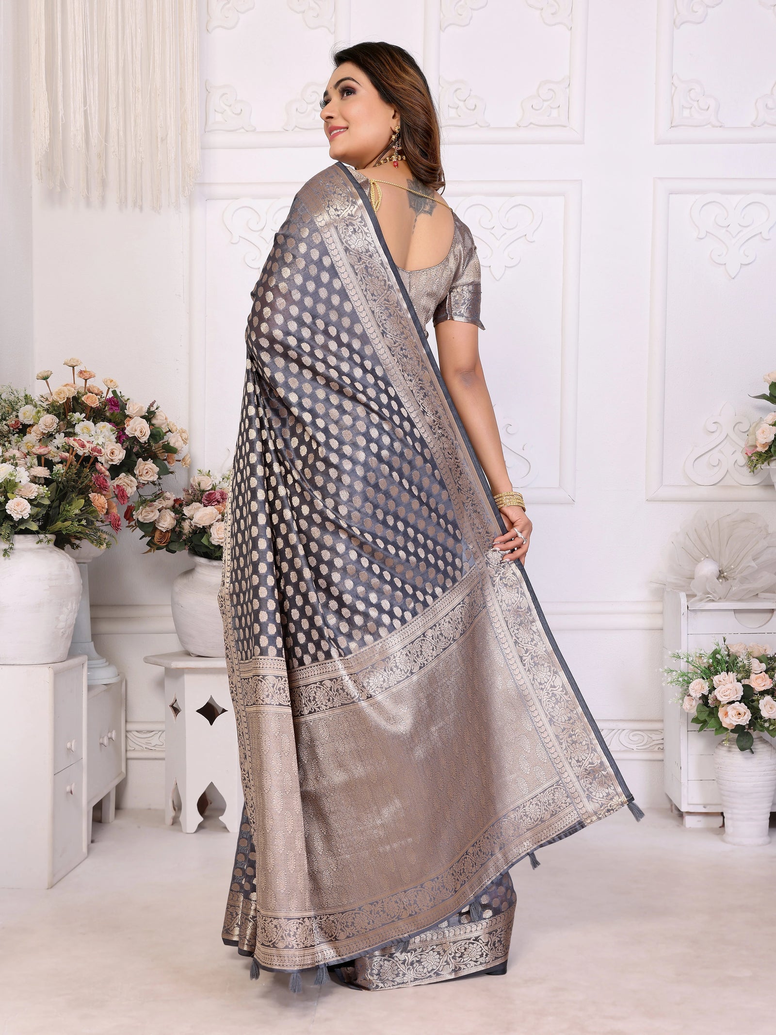 Woman wearing a traditional saree in a decorated room with flowers.