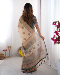 Woman wearing a patterned saree in a bright room with flowers and decor items.