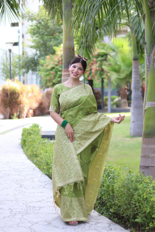 Woman wearing light pista traditional weaving saree posing gracefully in an outdoor garden setting