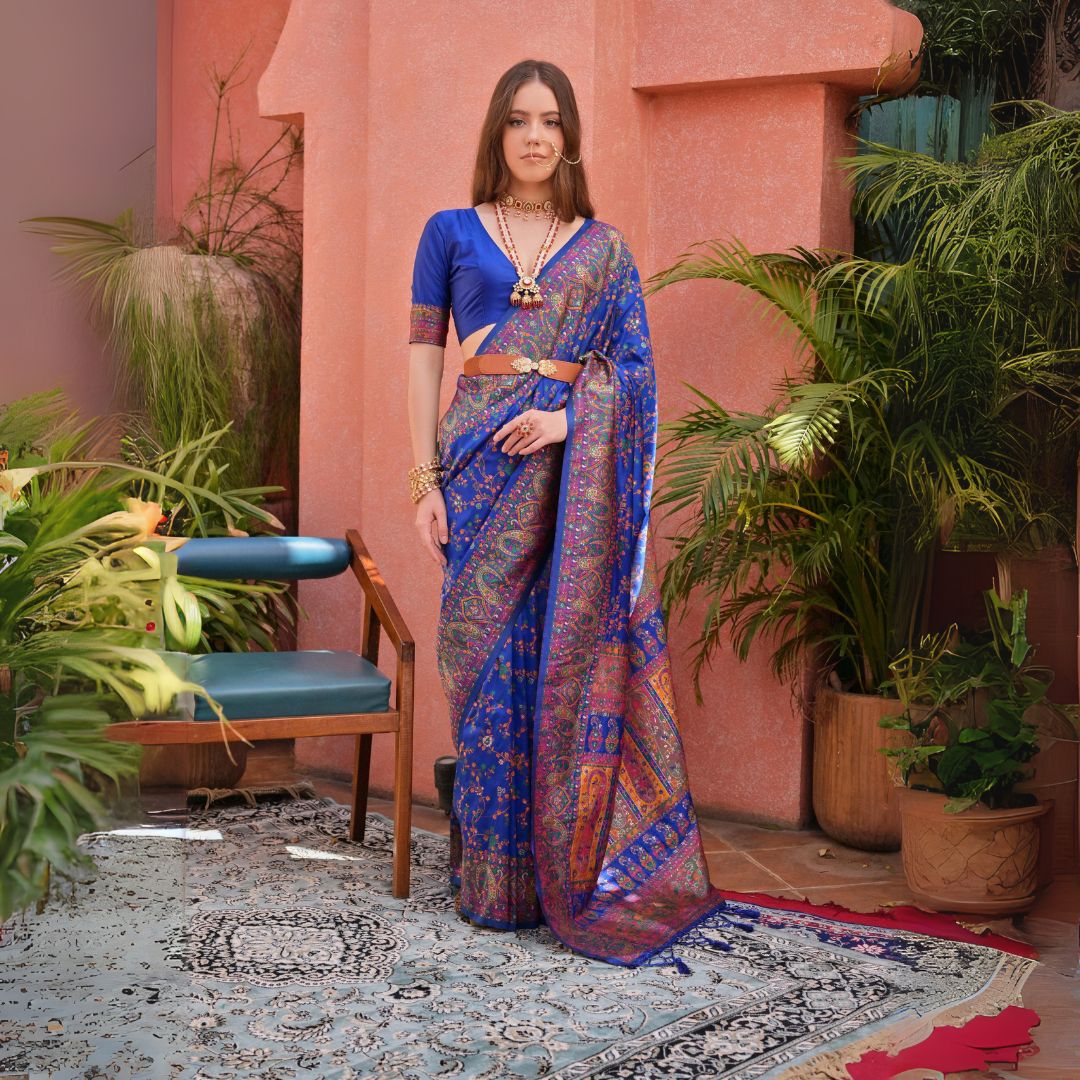 Woman wearing navy blue Kashmiri Jal weaving saree with intricate patterns in a lush green outdoor backdrop
