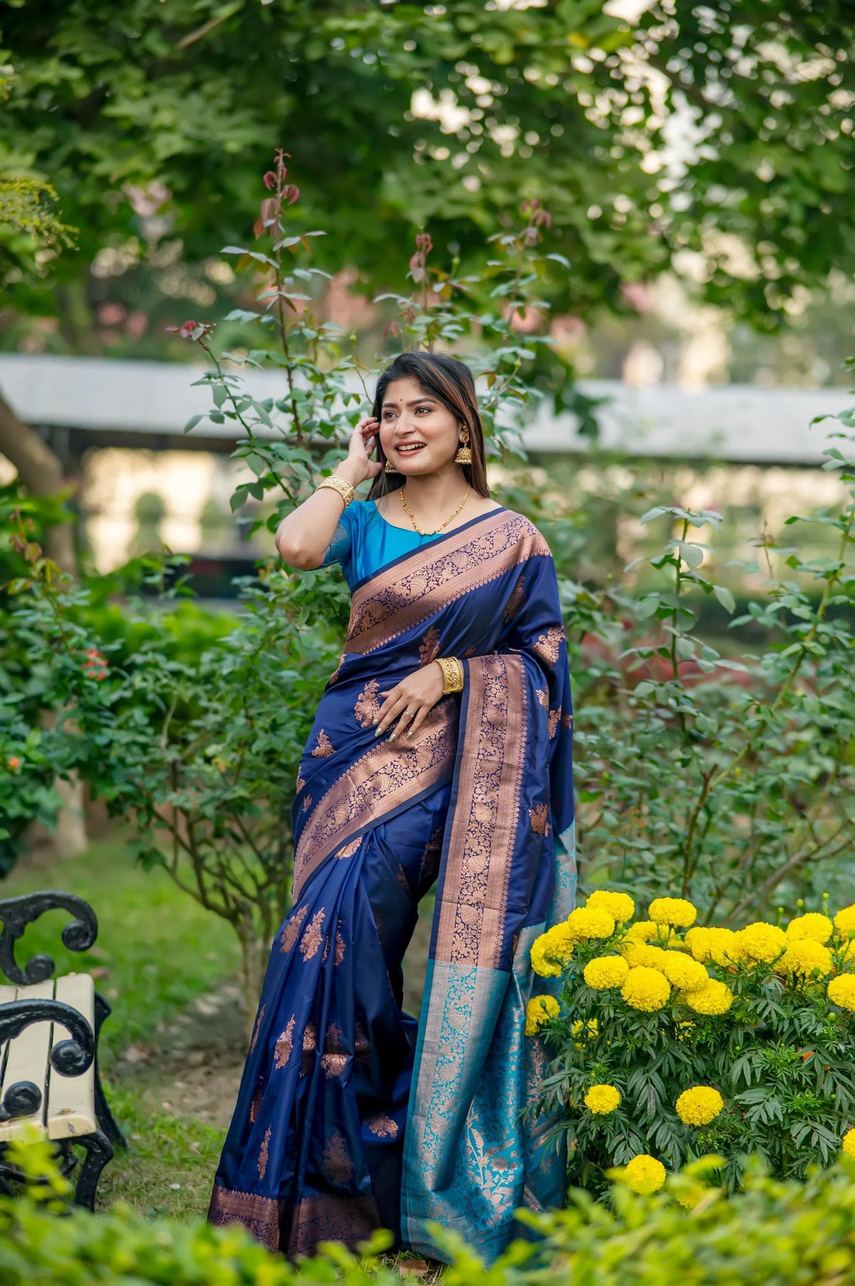 Woman in navy blue saree with zari work sitting outdoors