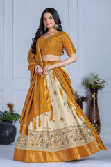 Woman wearing a mustard yellow and beige saree with a white wall background