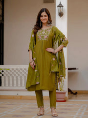 Woman wearing a green traditional outfit with floral embroidery indoors.