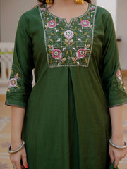 Green embroidered kurta worn by a person, with a blurred indoor background.