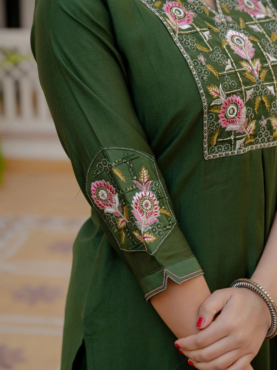 Green embroidered traditional outfit with floral patterns on a blurred background