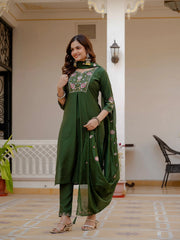 Woman wearing a green traditional outfit with floral embroidery in an indoor setting.