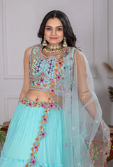 Woman wearing a traditional outfit with a turquoise lehenga and colorful blouse.