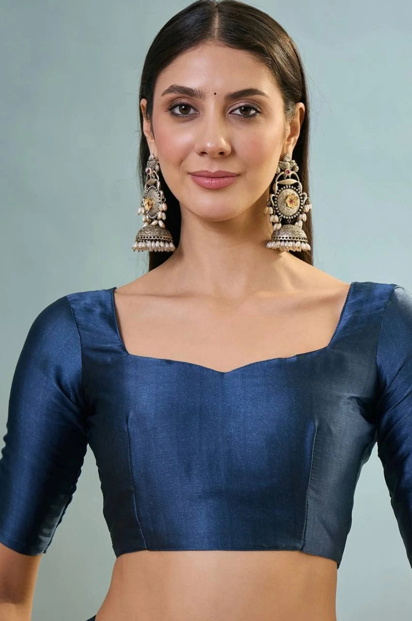 Woman wearing a blue blouse with long earrings against a light gray background