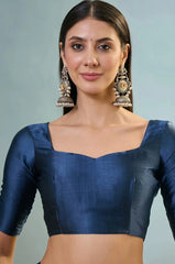 Woman wearing a blue blouse with long earrings against a light gray background