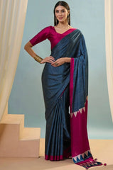 Woman wearing a blue and pink saree with a plain background