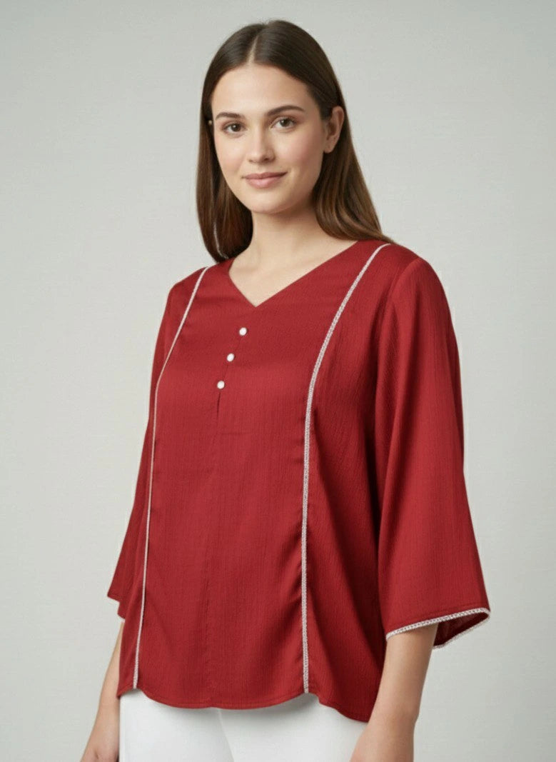 Woman wearing a red blouse with white trim on a plain background