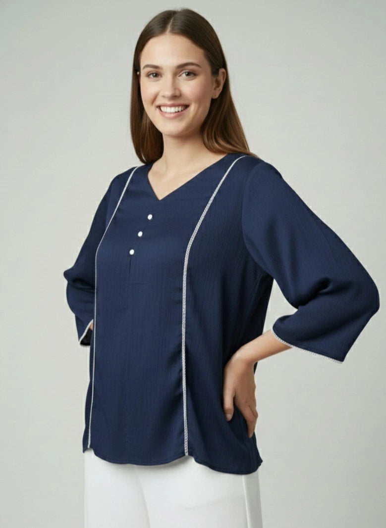 Woman wearing a navy blue blouse with white trim on a light gray background