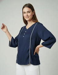 Woman wearing a navy blue blouse with white trim on a light gray background