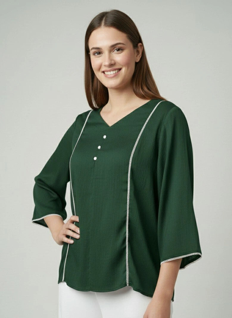 Woman wearing a green blouse with white trim on a gray background