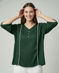 Woman wearing a green blouse with white trim on a plain background