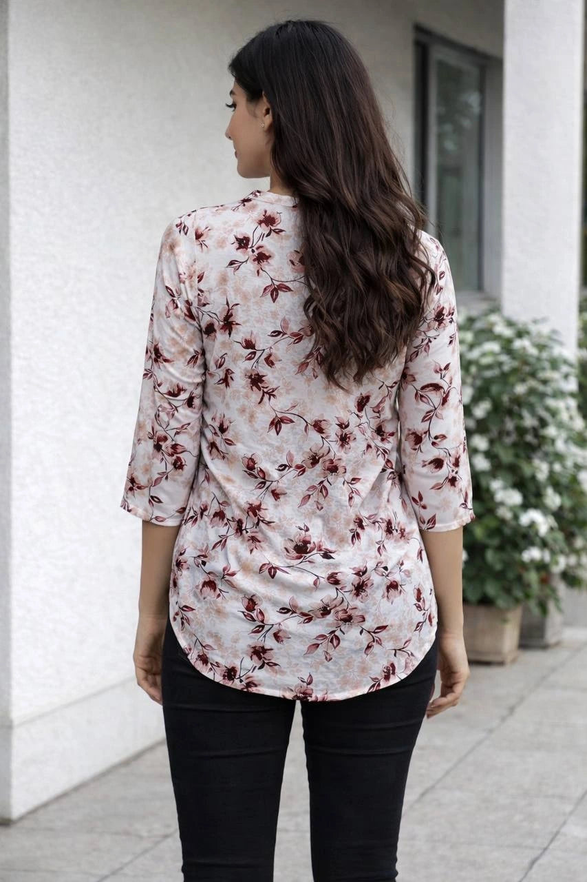 Woman wearing a floral blouse and black pants standing outdoors.