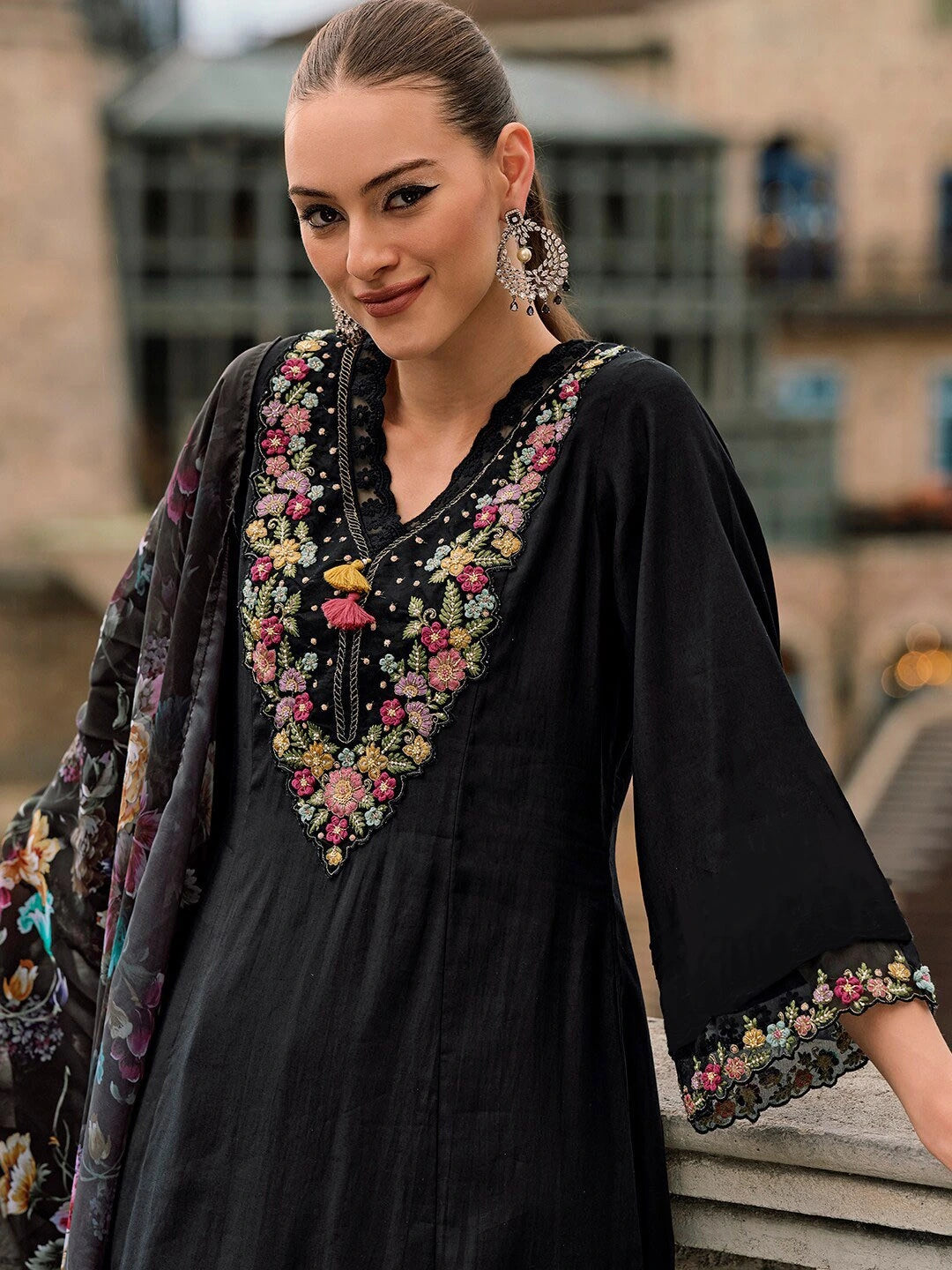 Woman wearing a black dress with floral embroidery in an outdoor setting