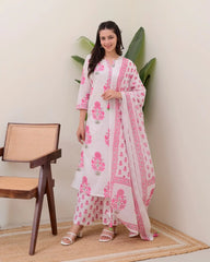 Woman wearing a white and pink floral outfit with a matching dupatta, standing indoors.